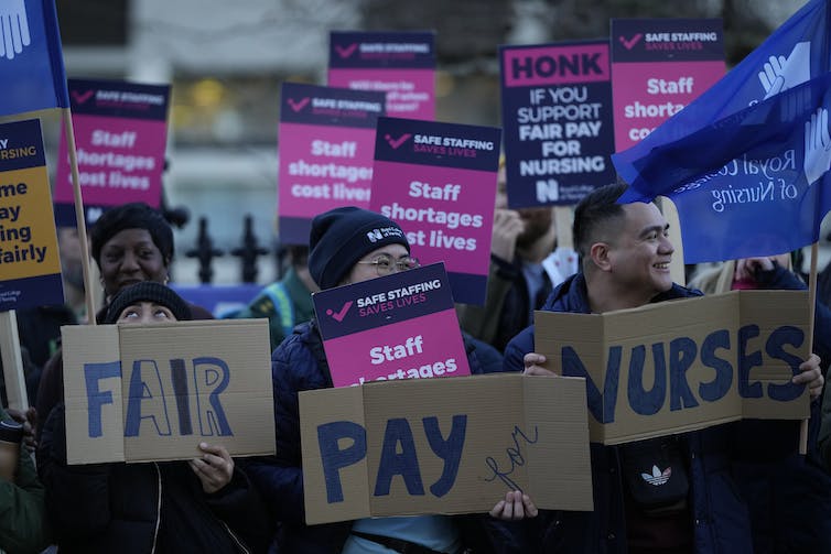 People holding signs reading 'Fair Pay for Nurses' and 'Staff shortages cost lives'