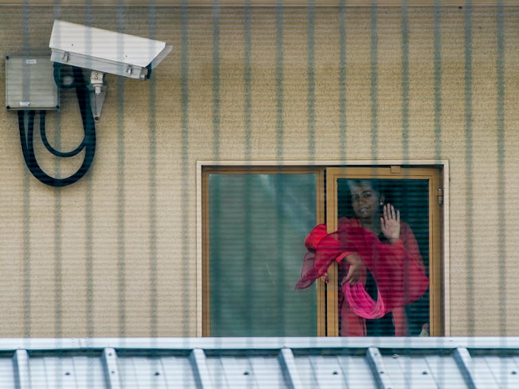 Woman waving in the window of a detention centre