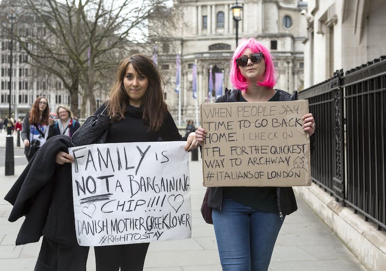 Two women holding up protest signs in London against Europeans being used as Brexit 'bargaining chips'.