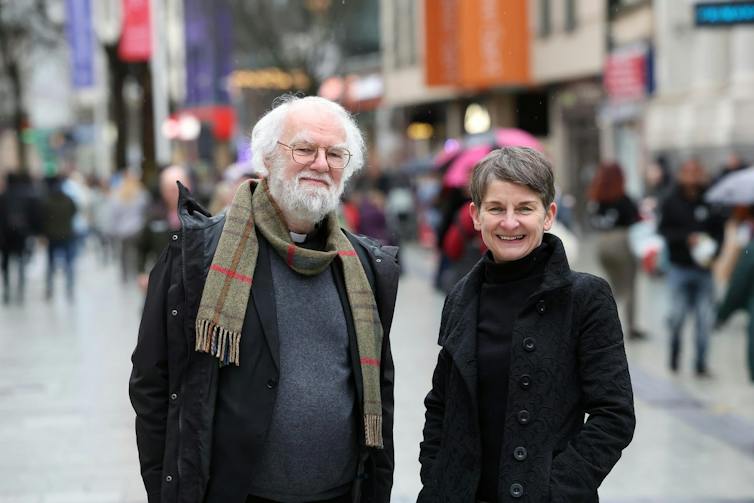 Rowan Williams stands next to Laura McCallister in the middle of a shopping street.