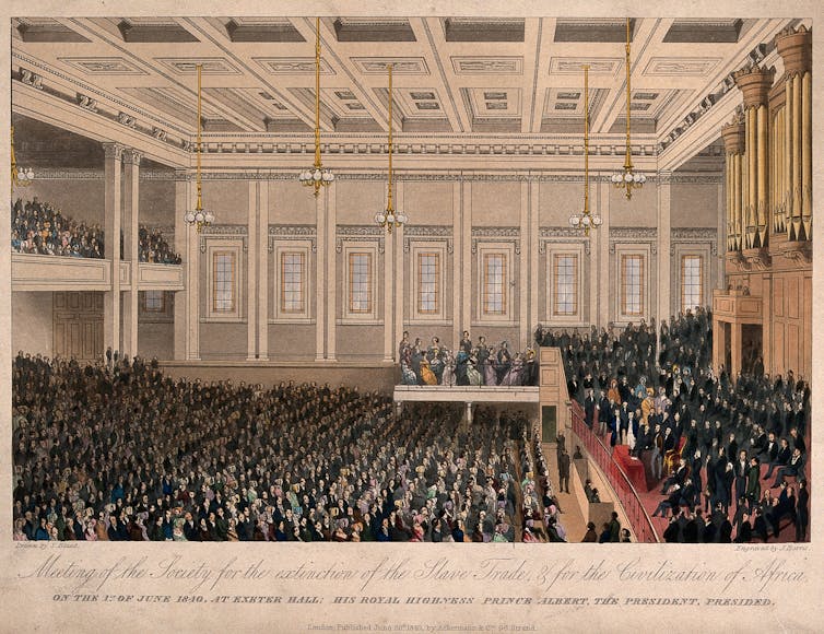 A crowded meeting in an ornately designed auditorium in the 19th century.